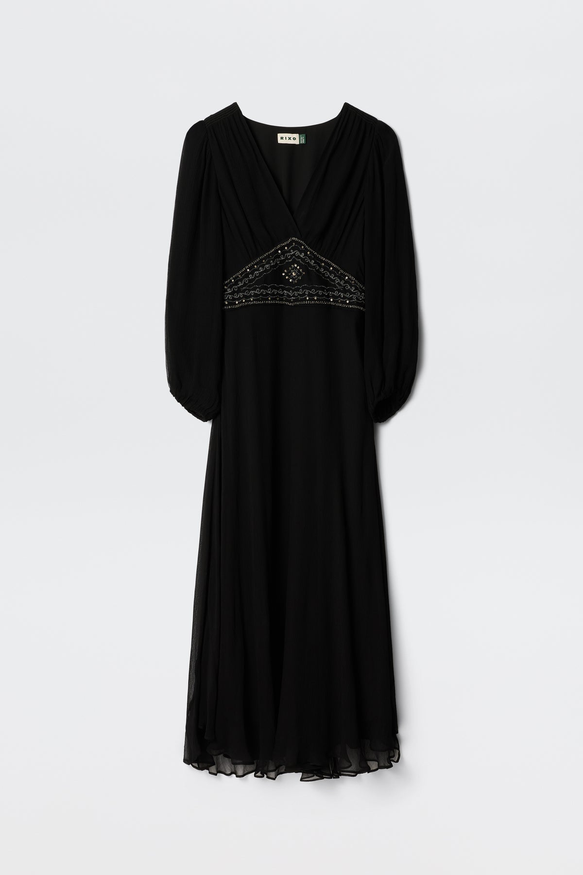 The Kaesha - Diana Embellishment Black dress features a V-neck, three-quarter sleeves, beaded detail under the bust, sheer hem and sleeves, and a softly draped flowing skirt. Shown hanging against a plain background.