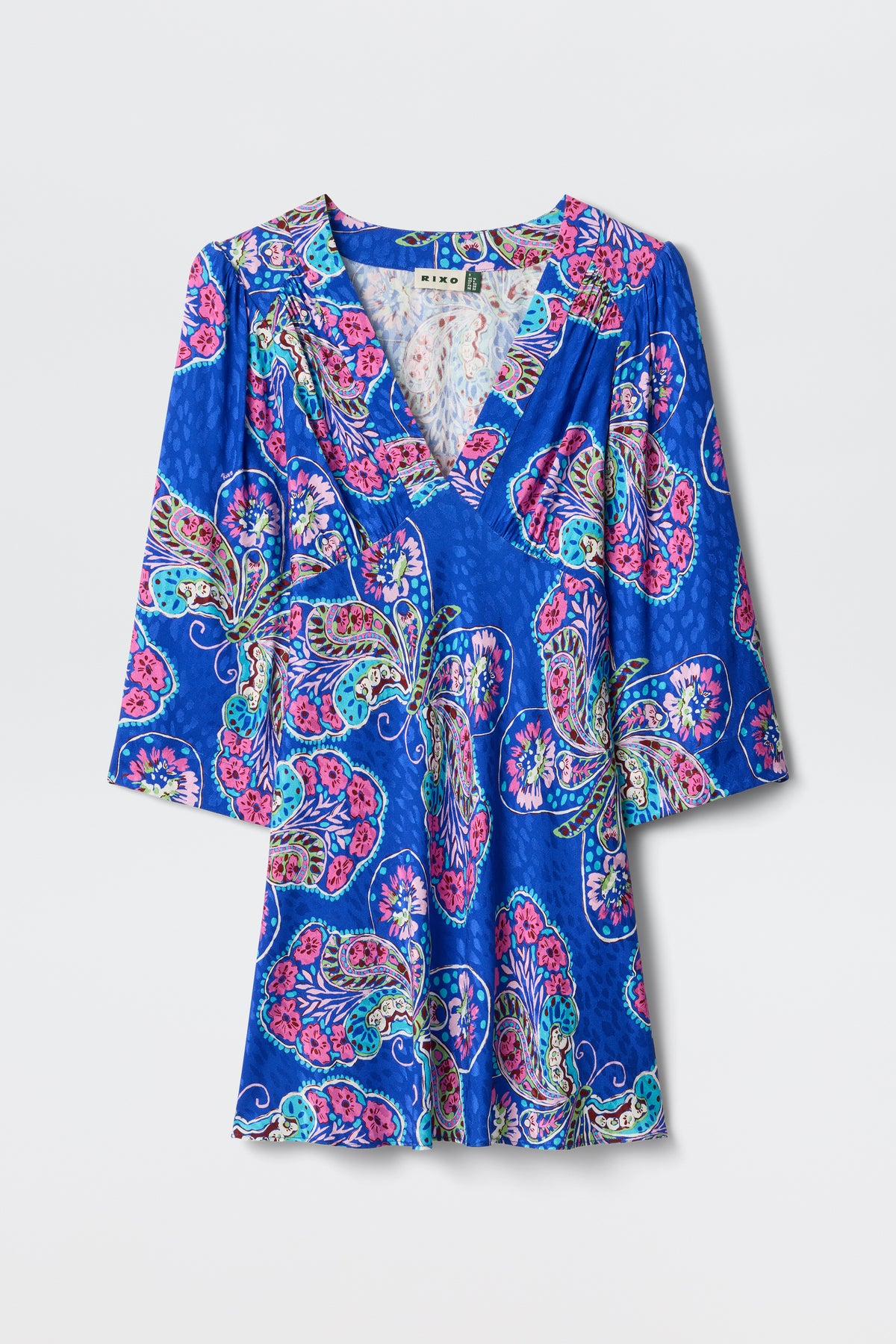 The Margaux - Butterfly Bloom Jacquard Blue dress is a blue V-neck with 3/4 sleeves, a colorful pink, purple, and teal pattern, a subtle sheen, and a relaxed, flowy fit.