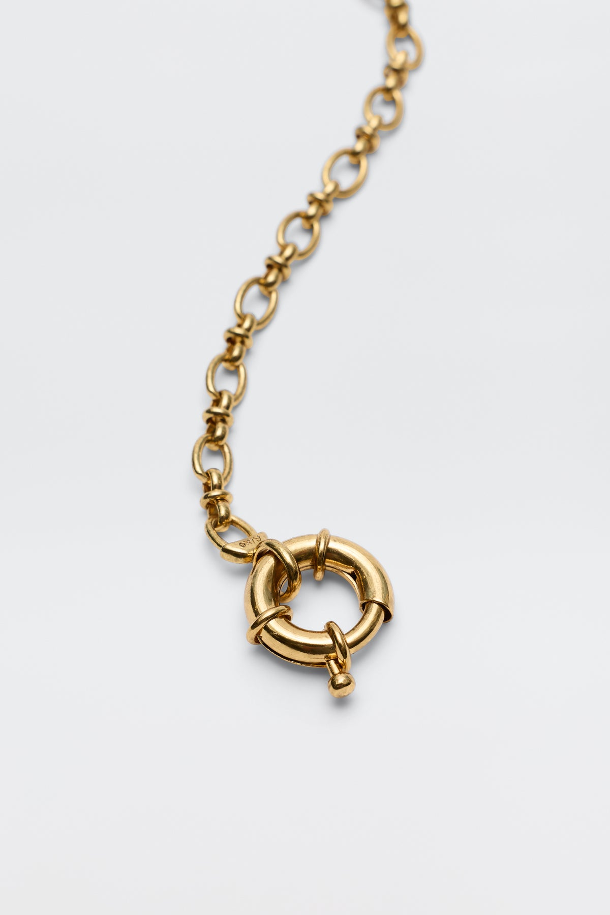 A close-up of the Lorene - Gold necklace, highlighting its large circular spring ring clasp—ideal for adding charms and customizing your own look—centered on a plain white background.