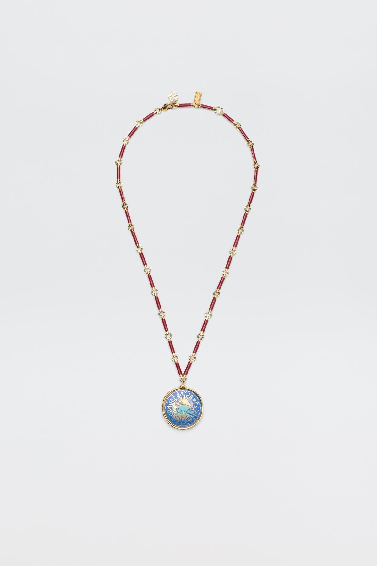 The Ari - Astro Cancer necklace features gold statement disc charms with alternating red and gold links and a round blue-and-gold sunburst pendant. Ideal as a zodiac necklace, it's shown on a plain white background.