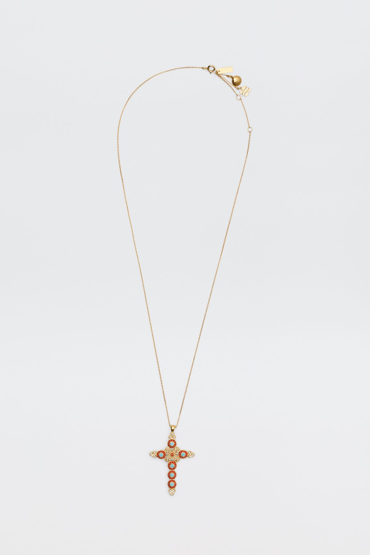The Lenka - Gold necklace features a gold chain with a cross pendant embellished with red and clear stones, shown against a plain white background.