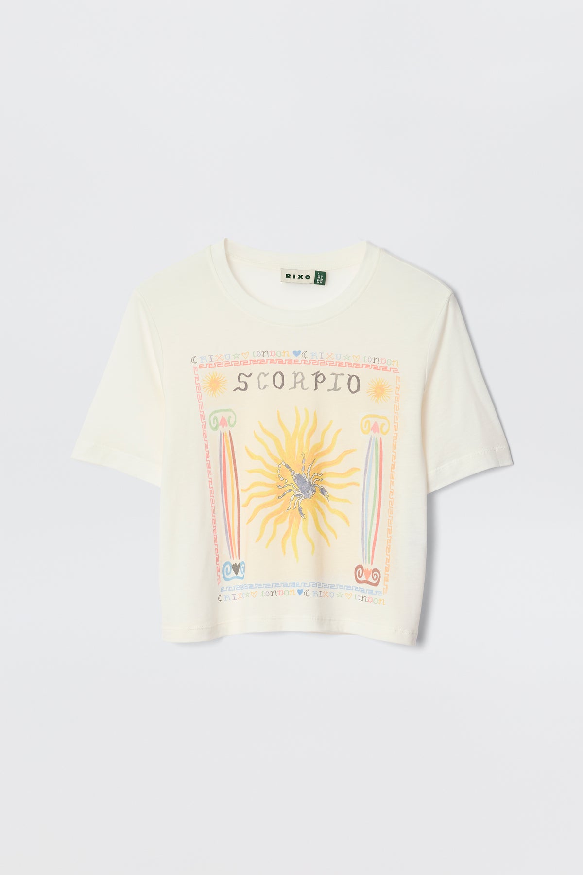 The Ria - Scorpio is a white cropped T-shirt with a vibrant Scorpio illustration—sun, scorpion, and zodiac symbols—designed to pair perfectly with RIXO skirts. Laid flat on a plain background for an eye-catching astrological statement.