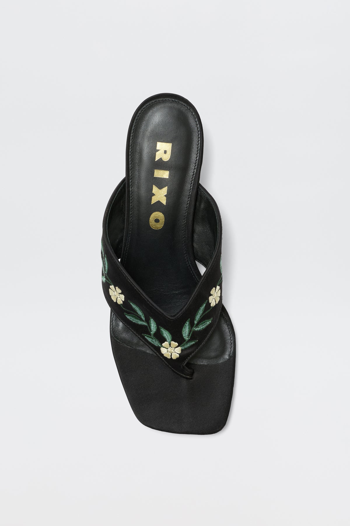 The Zoya - Blossom Embroidery Black sandals showcase a black satin finish, square toe, gold RIXO insole branding, and green and white floral embroidery on the straps, shown from above on a white background.