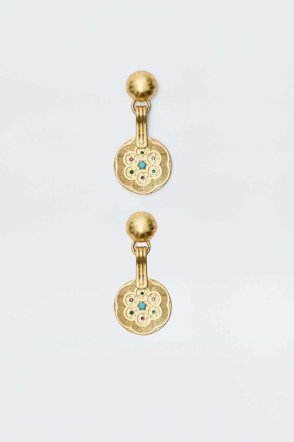 A pair of Anouk - Gold drop earrings with round, textured discs featuring a circular pattern and central colored gemstones, attached to smooth gold studs. Vintage-inspired, photographed on a plain white background.