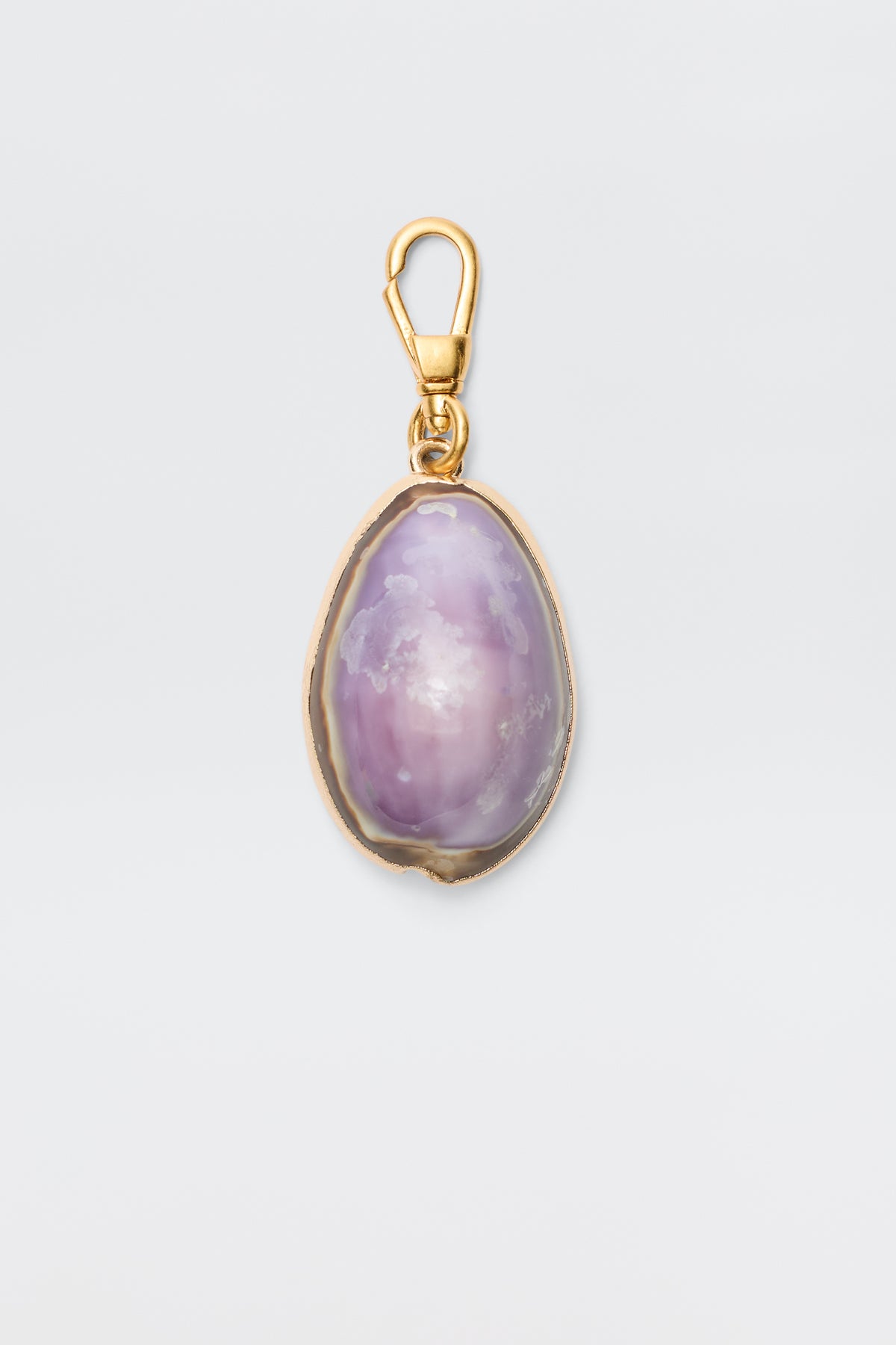Cowrie - Lavender: An elegant bohemian pendant with a gold clasp and frame, showcasing a polished oval purple stone with white and light pink marbling, set against a plain light background.