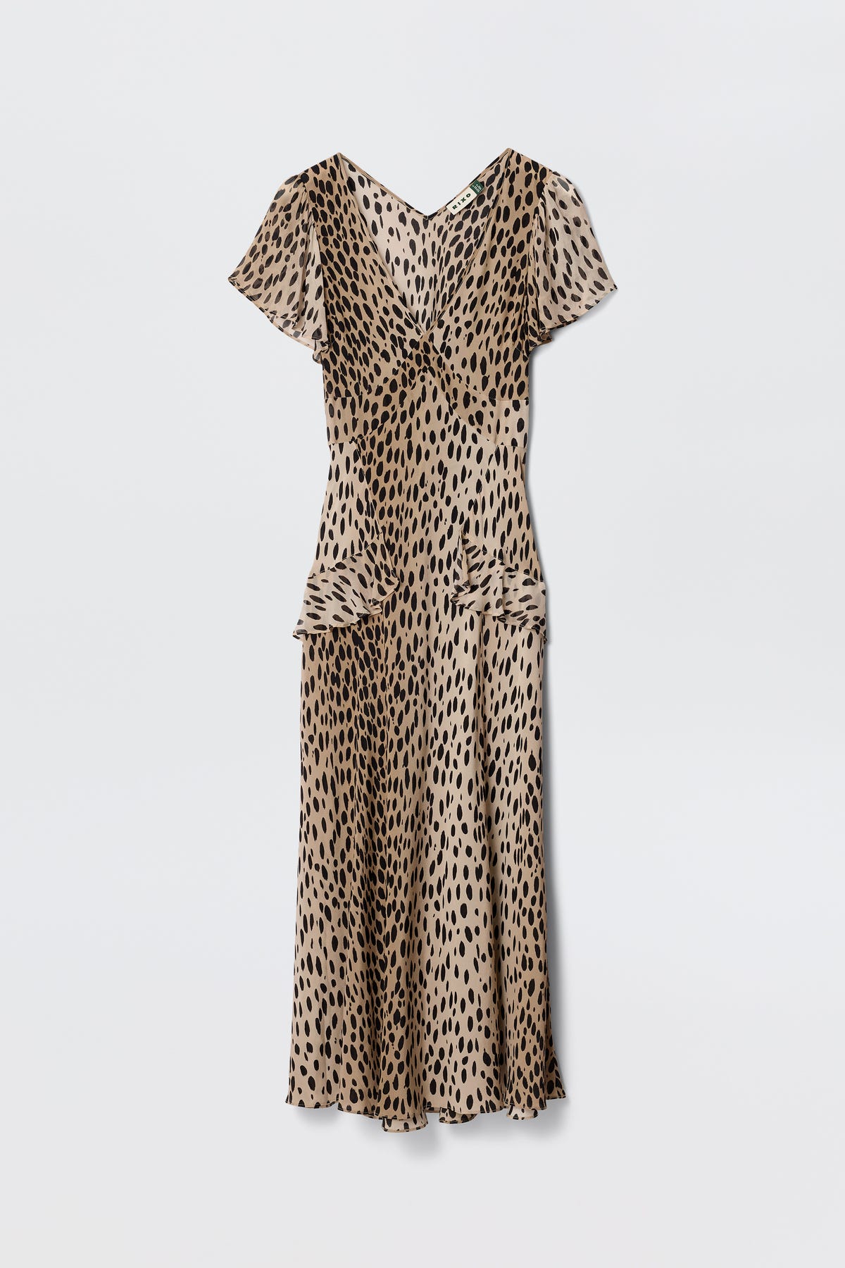 The Evie - Antelope Spot Black dress features a beige base with black irregular spots, short sleeves, V-neck, and midi length, offering a bohemian animal print vibe. Shown against a plain white background.
