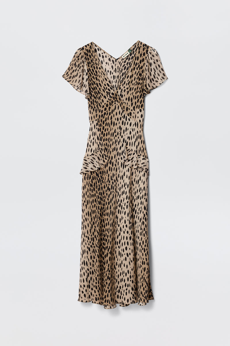 The Evie - Antelope Spot Black dress features a beige base with black irregular spots, short sleeves, V-neck, and midi length, offering a bohemian animal print vibe. Shown against a plain white background.