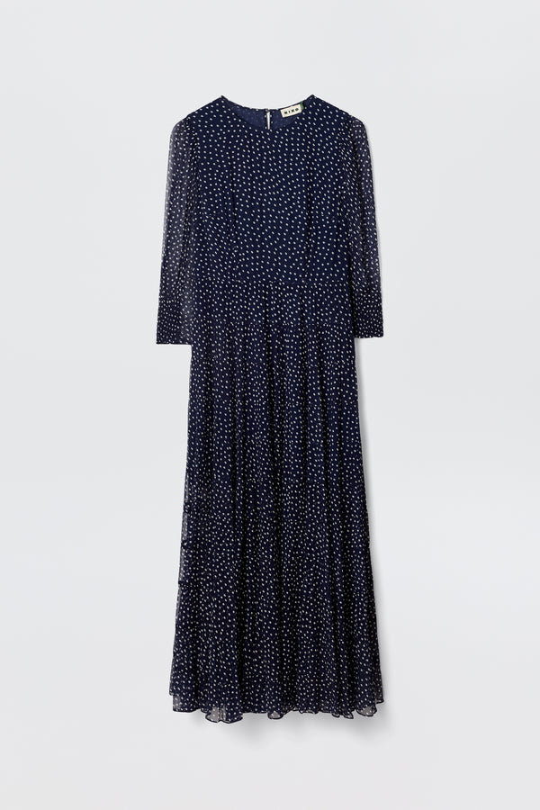The Kristen - Navy Polka Dot dress features a navy georgette fabric, long sleeves, ankle-length tiered skirt, ivory polka dots, round neckline, and a slightly flared silhouette, displayed on a plain light background.