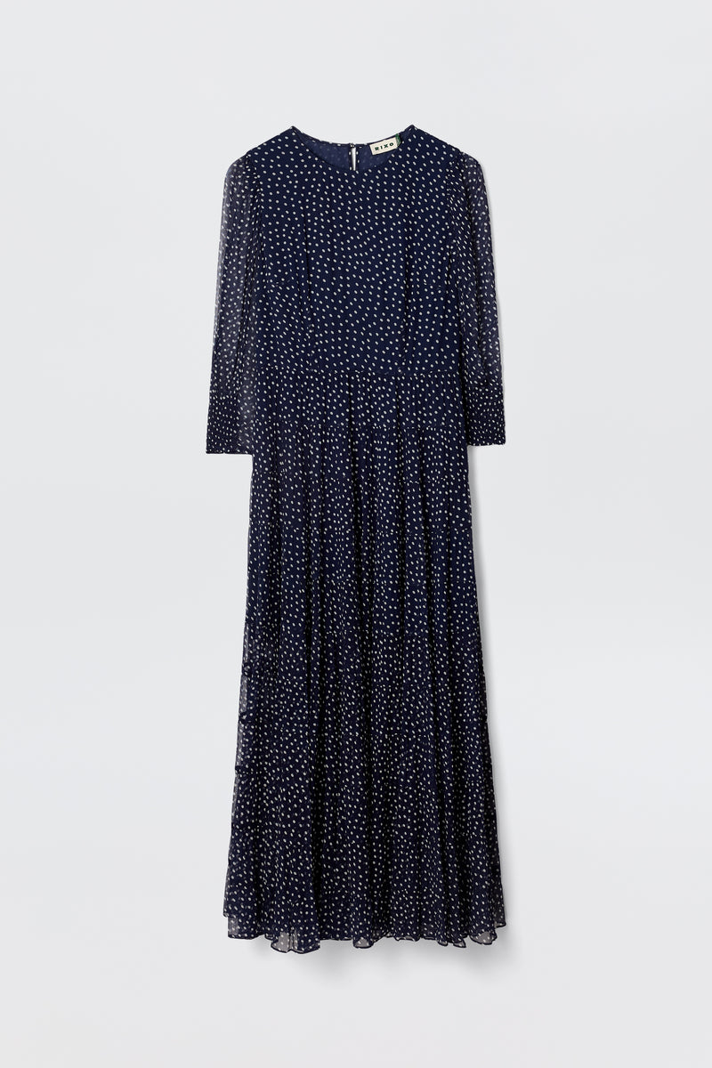 The Kristen - Navy Polka Dot dress features a navy georgette fabric, long sleeves, ankle-length tiered skirt, ivory polka dots, round neckline, and a slightly flared silhouette, displayed on a plain light background.