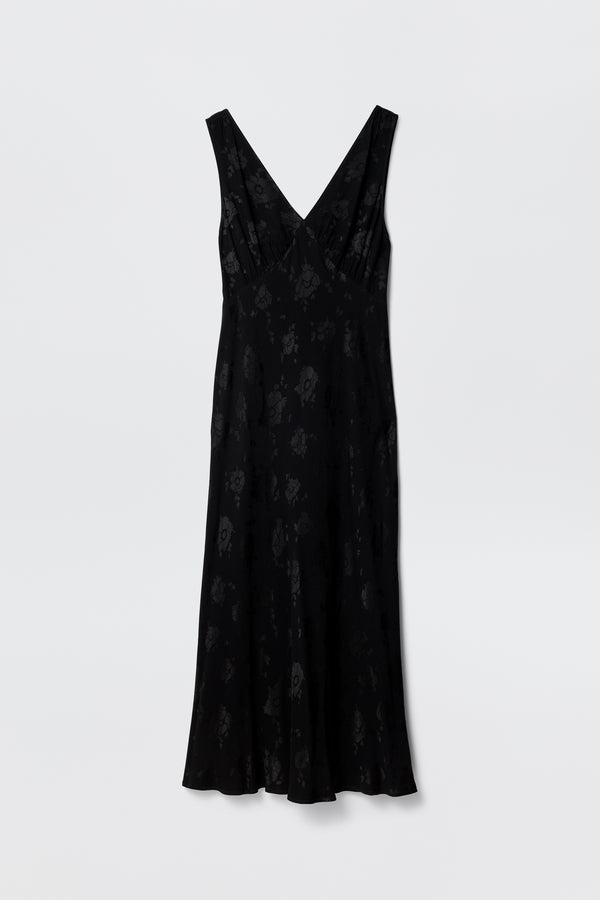 The Sandrine - Black Poppy Jacquard is a sleeveless midi dress with a subtle poppy floral jacquard pattern, deep V-neckline, and slightly flared hem, shown against a plain white background.
