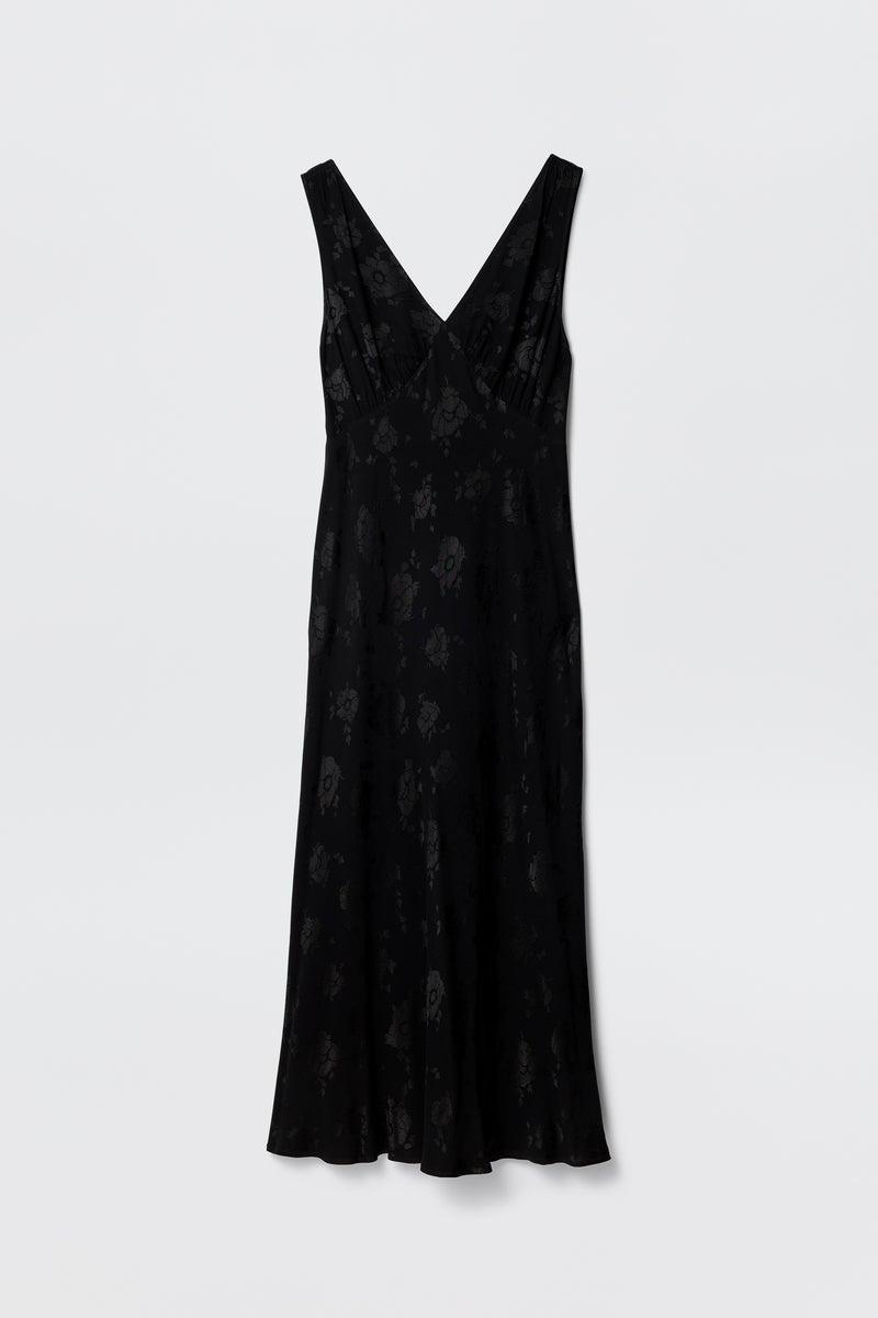 The Sandrine - Black Poppy Jacquard is a sleeveless midi dress with a subtle poppy floral jacquard pattern, deep V-neckline, and slightly flared hem, shown against a plain white background.