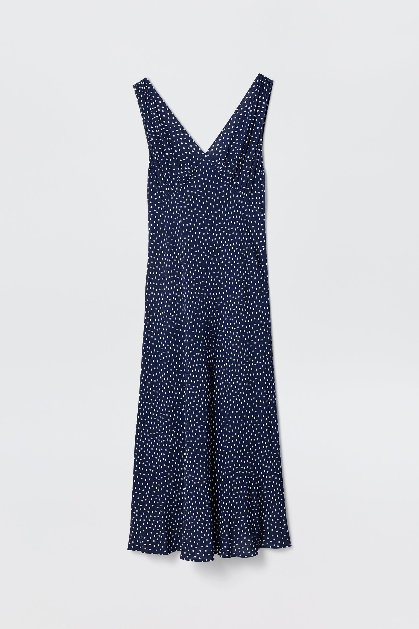 The Sandrine - Mini Dot Navy is a vintage-inspired, navy blue bias-cut slip dress featuring a V-neckline and chic white polka-dot print, shown against a plain white background.
