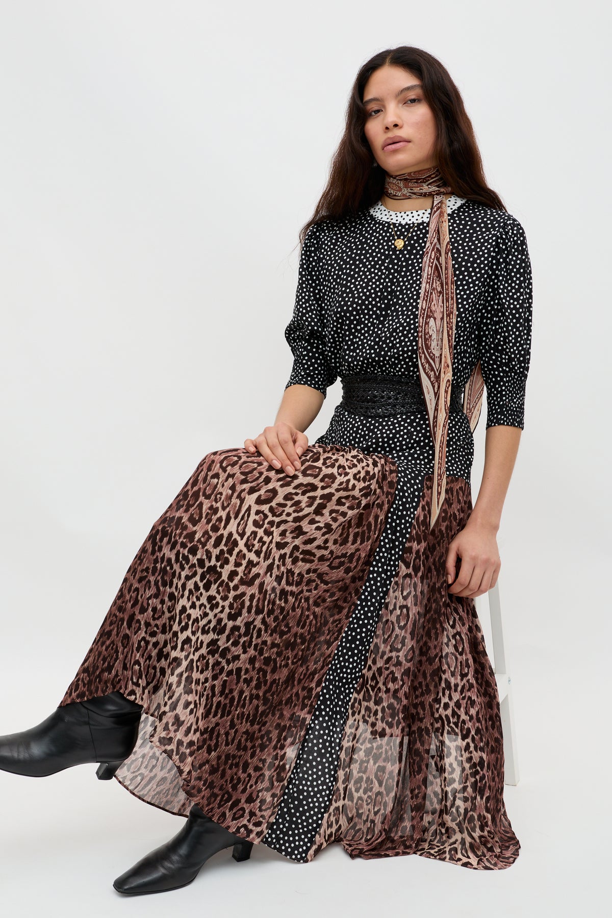 A woman with long dark hair sits on a stool wearing the "meg - leopard polka dot" against a plain white background.