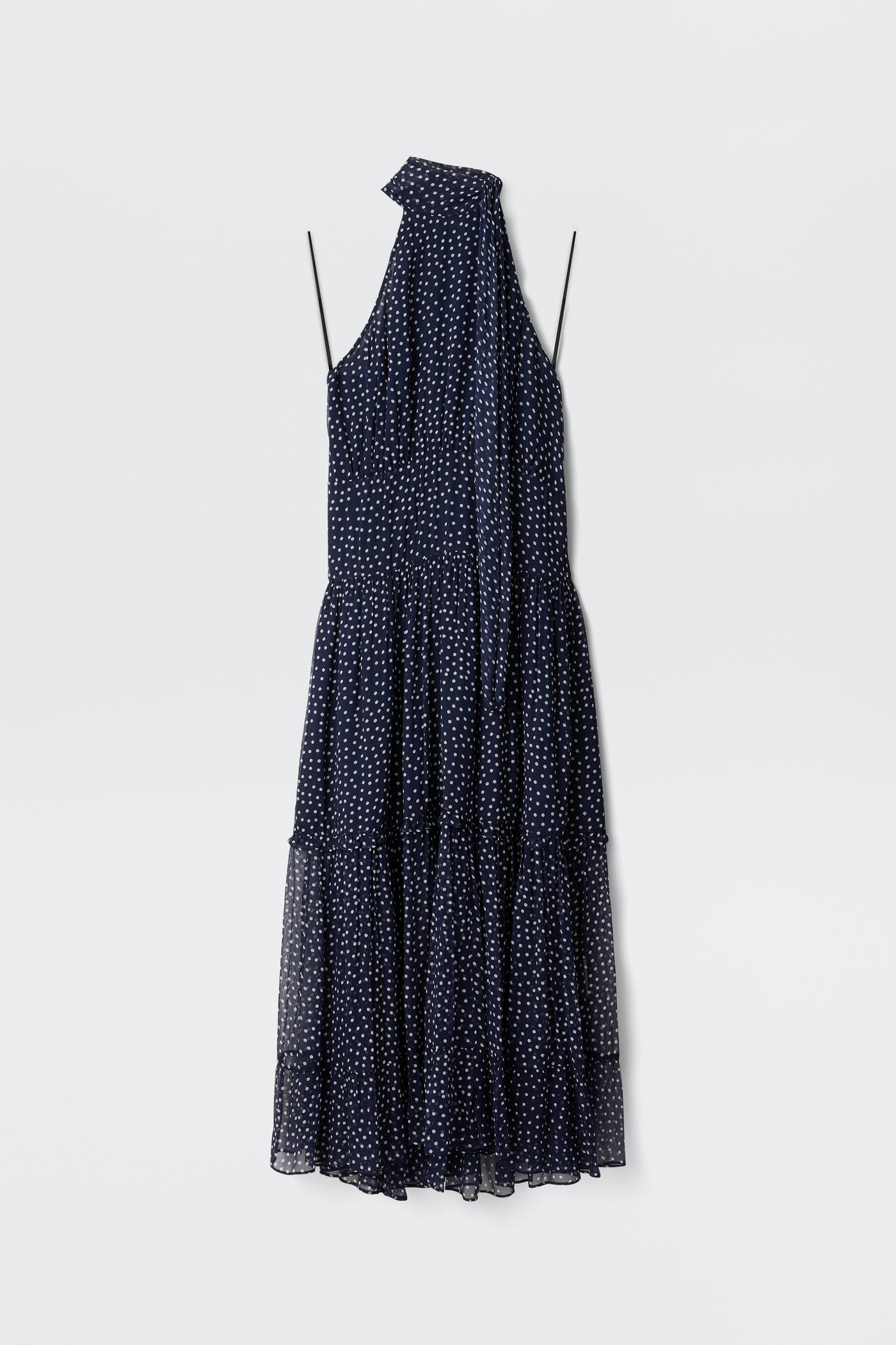 The Abi - Mini Navy Polka Dot is a sleeveless navy georgette mini dress with white polka dots, thin straps, a halter neckline, and an attached scarf detail, shown against a plain white background.