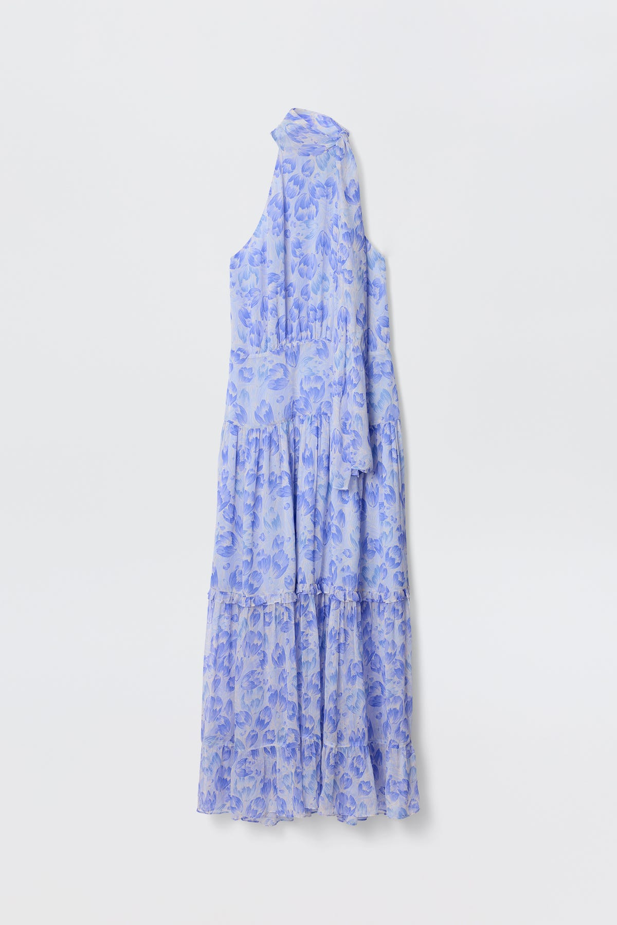 The Abi - Tulip Fields Cornflower Blue is a sleeveless, ankle-length georgette dress with a high neck, asymmetrical one-shoulder design, and a light blue and purple vintage tulip print, shown against a plain white background.