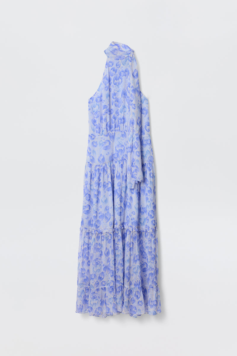 The Abi - Tulip Fields Cornflower Blue is a sleeveless, ankle-length georgette dress with a high neck, asymmetrical one-shoulder design, and a light blue and purple vintage tulip print, shown against a plain white background.