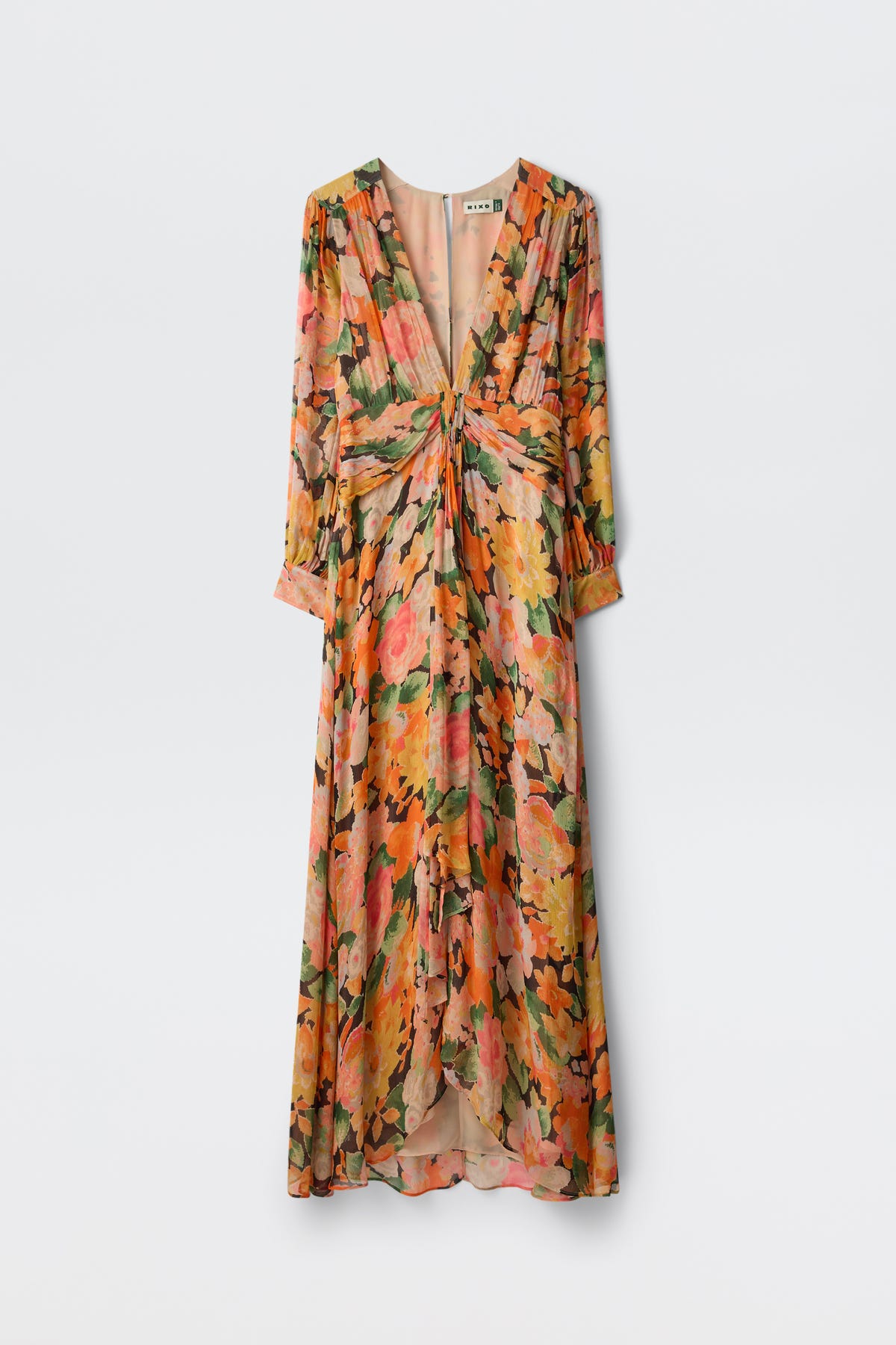 The Meera - Chelsea Floral Black is a long-sleeved maxi dress with a deep V-neck, ruched waist, and large orange, pink, and green floral pattern on a light background. It features a flowy silhouette and slightly puffed sleeves.