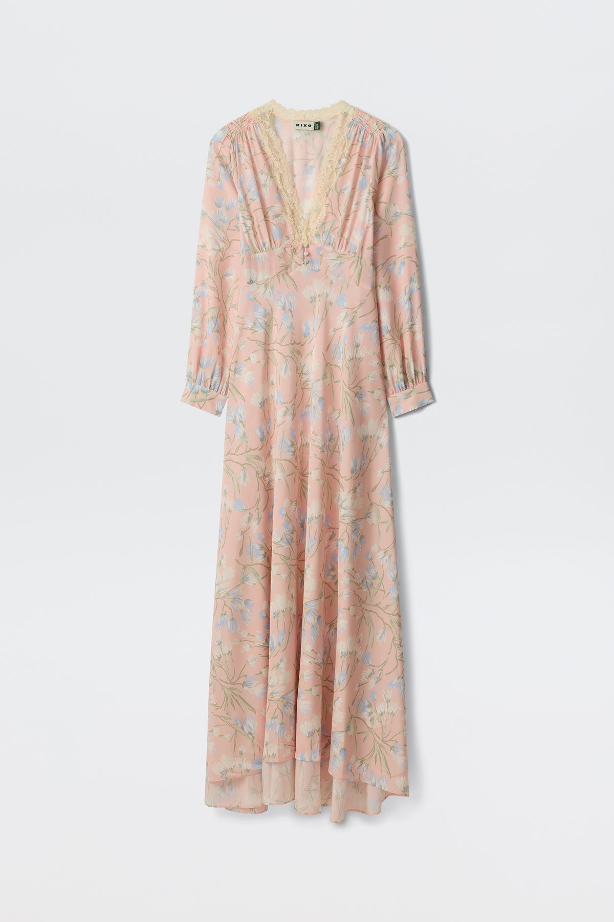 The Emory - Watercolour Floral Pink is a long, light pink dress featuring blue and green floral patterns, long sleeves, a lace-trimmed V-neckline, and an airy, flowing silhouette.