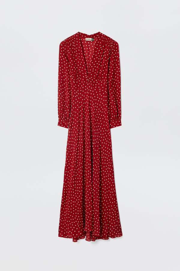 The Emory - Layla Dot Red is a long-sleeved, floor-length gown with white polka dots, a V-neckline, and a flowing skirt, shown against a plain white background.
