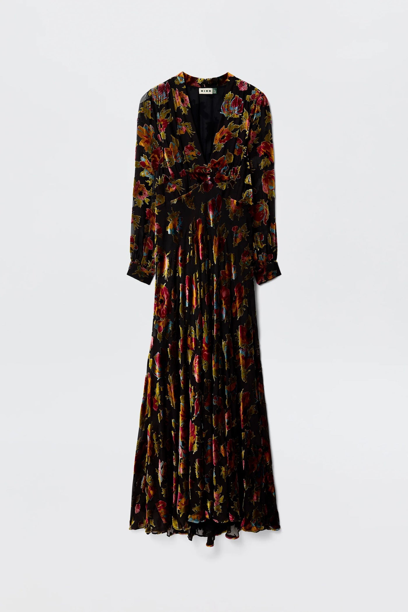 Elegant and eye-catching, the Emory - Countryside Devoré Black is a long black maxi dress with a deep V-neck, long sleeves, vibrant red, yellow, and green floral print, fitted waist, and graceful pleated skirt—perfect for special occasions.
