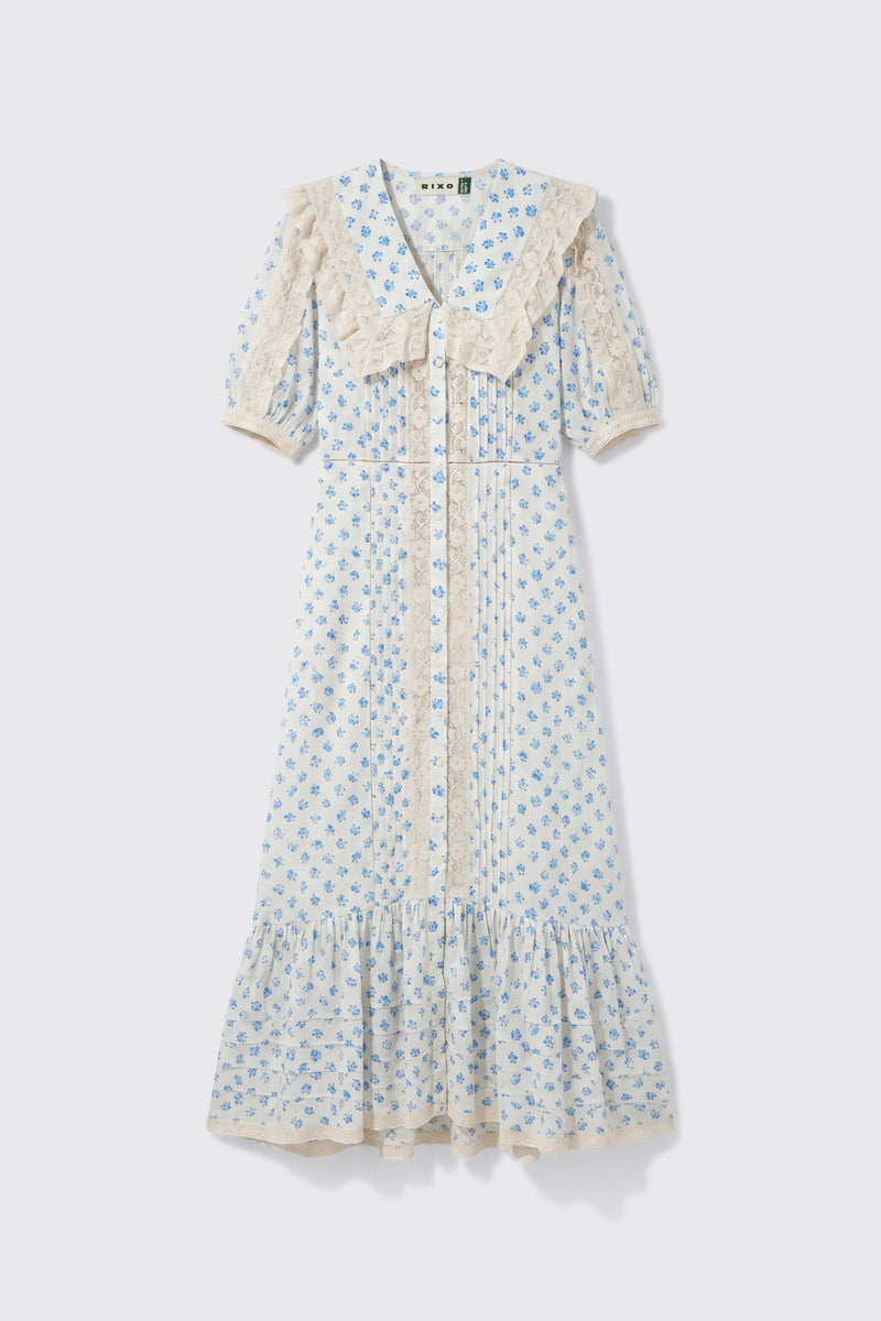 Edina - Seville Floral Cream dress featuring light blue floral patterns, short sleeves, lace trim, a large lace collar, front buttons, and a ruffled hem, displayed on a white background.