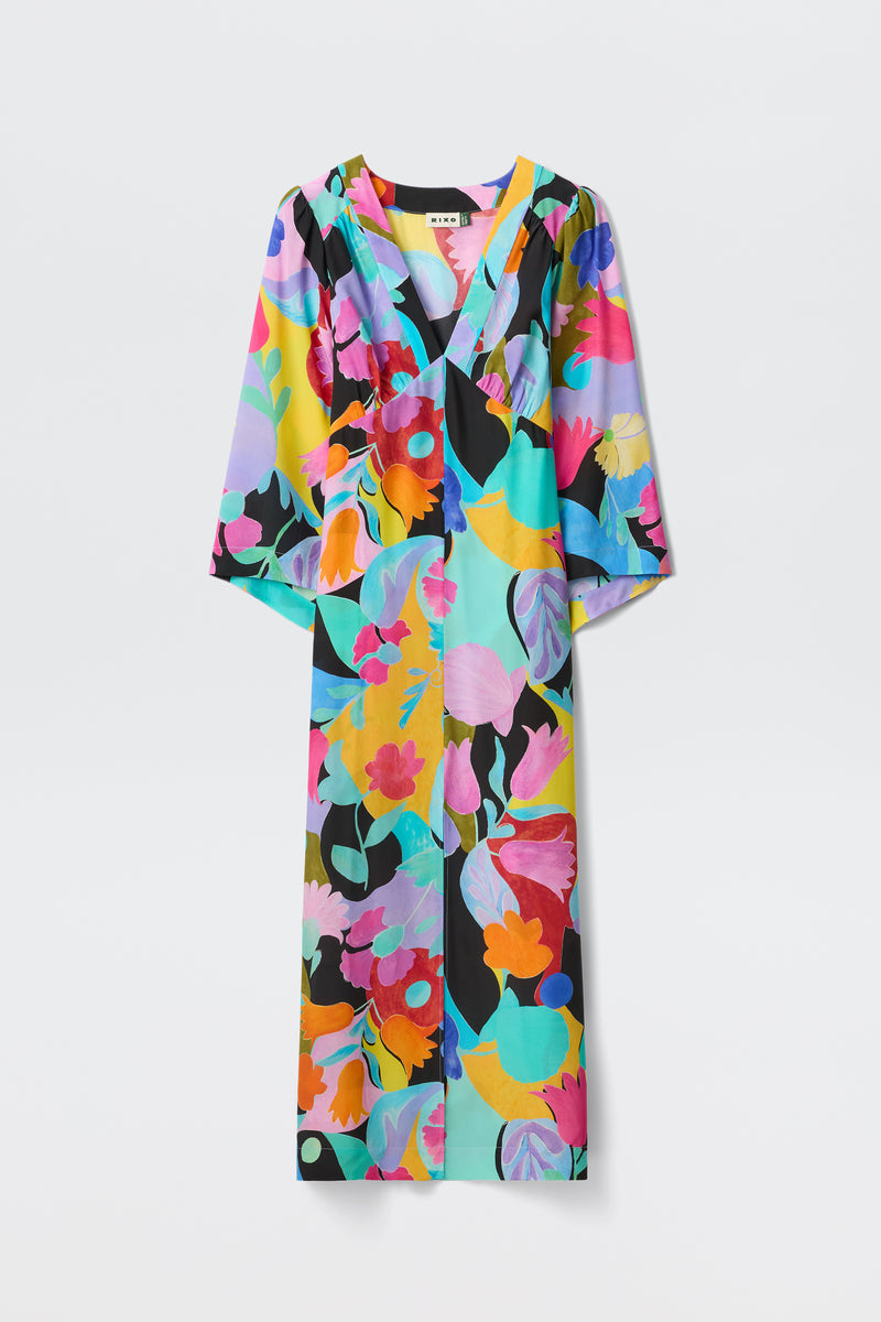 The Dahlia - Abstract Tulip Black is a long-sleeved V-neck dress with dramatic sleeves, featuring a bold, colorful floral print in pink, yellow, blue, purple, and green on a light background.