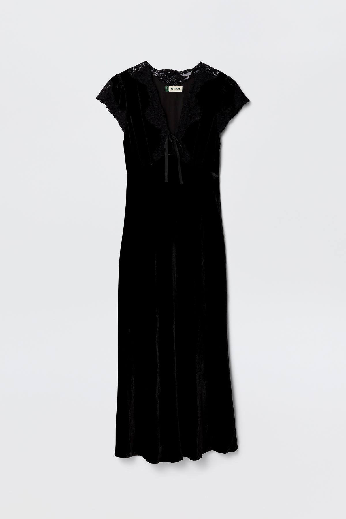 The Amari - Black dress features black velvet, an adjustable V-neck, short lace sleeves, lace trim at the shoulders and neck, and a ribbon bow tie detail at the front, shown against a plain white background.