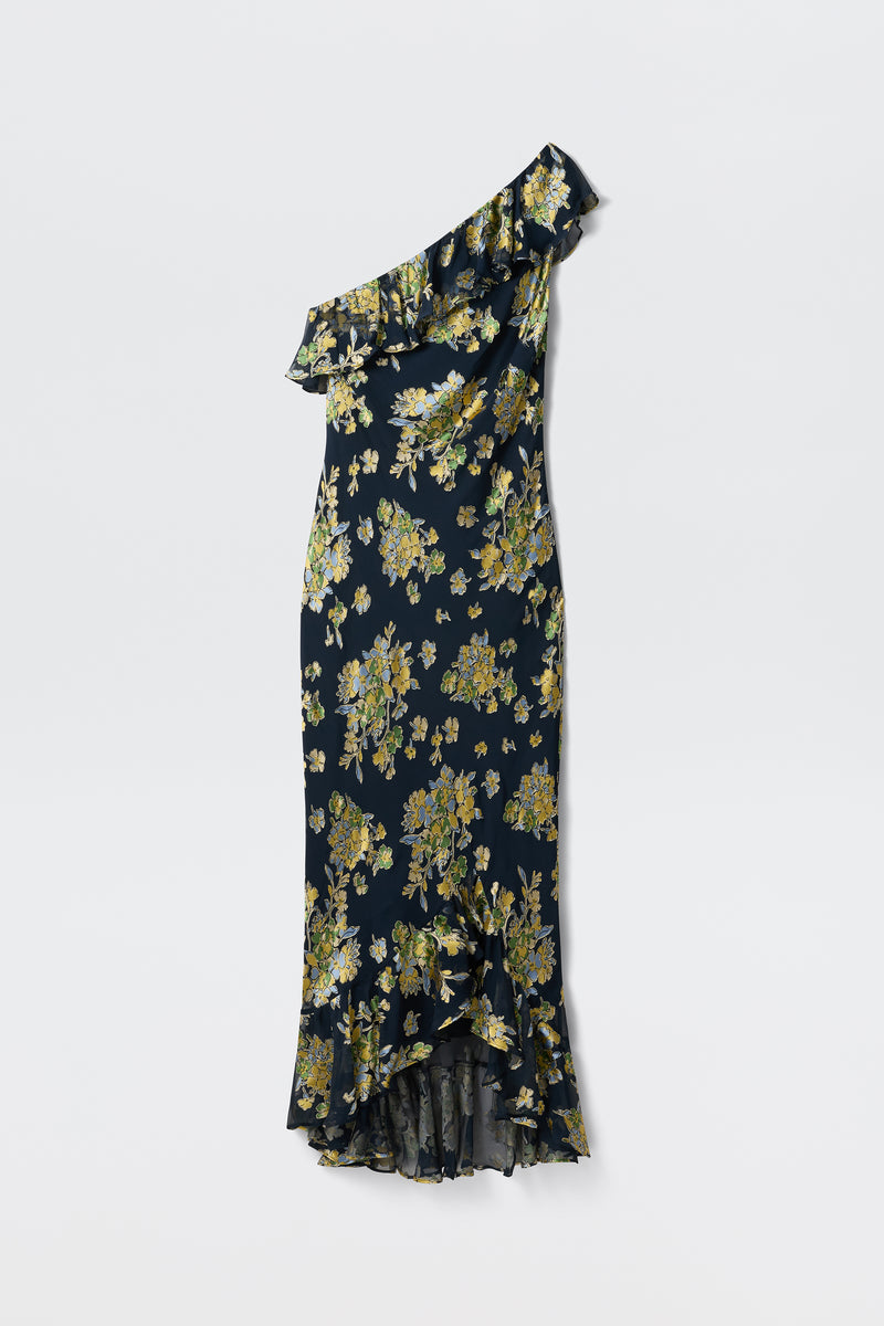The Leon - Bouquet Devoré Navy is a dark blue, one-shoulder dress featuring yellow floral patterns, ruffled trim along the neckline, and a ruffled hem. Displayed against a plain white background.