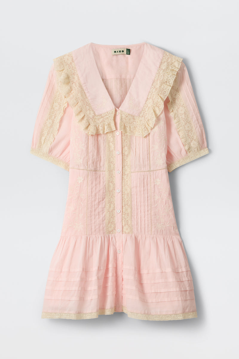 The Dove - Pansy Embroidery Vintage Pink dress in soft cotton-voile features cream lace embroidery, a large ruffled collar, embroidered details, and a button-down front, displayed against a plain background.