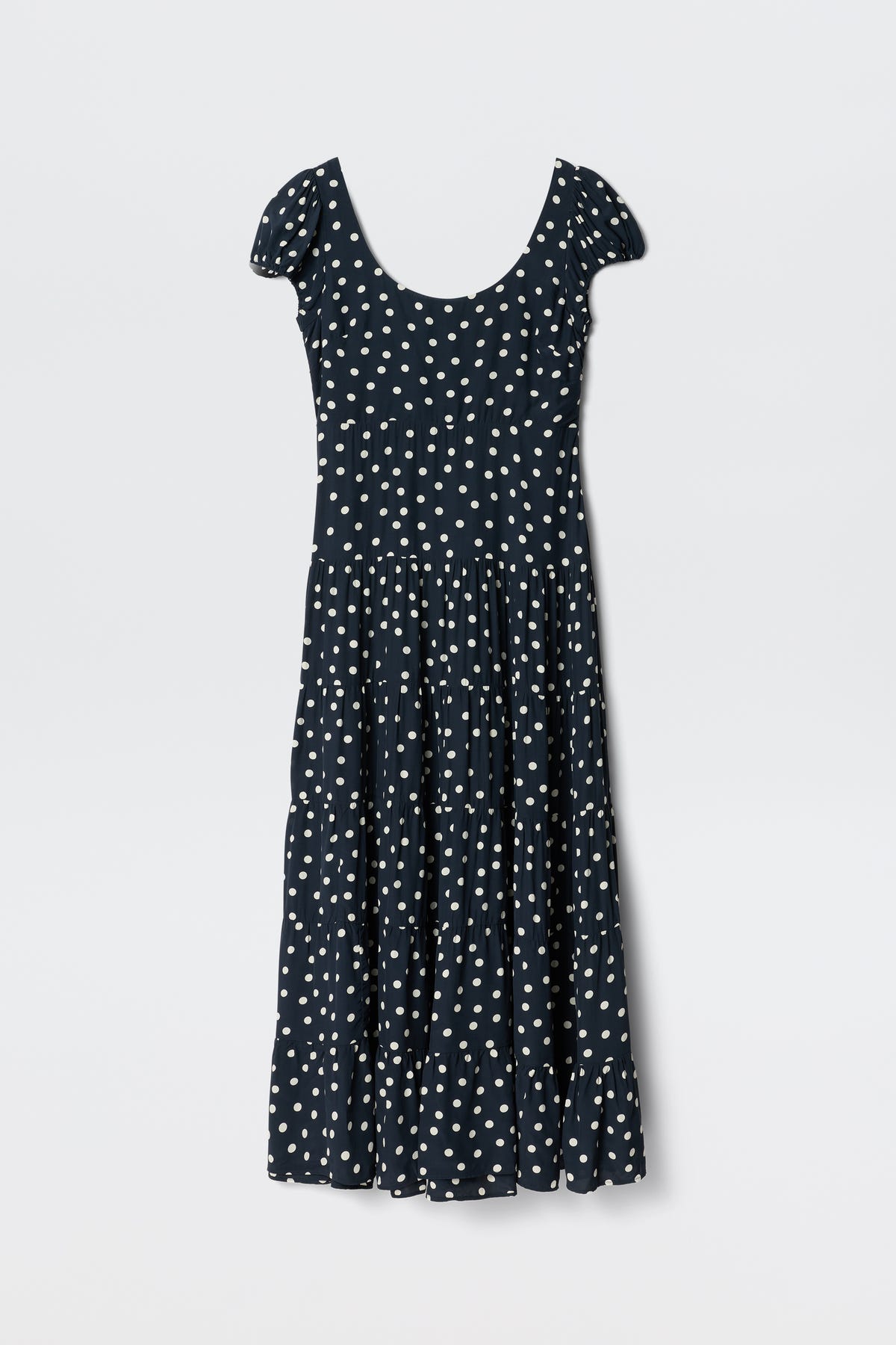 The Remi - Bohemia Spot Deep Navy dress features a scoop neck, white polka dots, short sleeves, and an ankle-length tiered skirt—ideal for summer and shown on a plain white background.