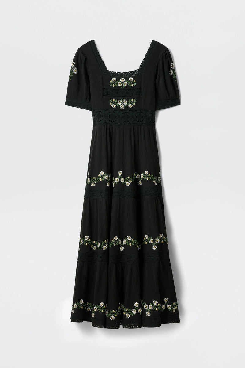 The Philippa - Lilia Embroidery Black is a black, ankle-length, short-sleeve dress with a square neckline and white-and-yellow floral embroidery in horizontal bands across the bodice, sleeves, and skirt.