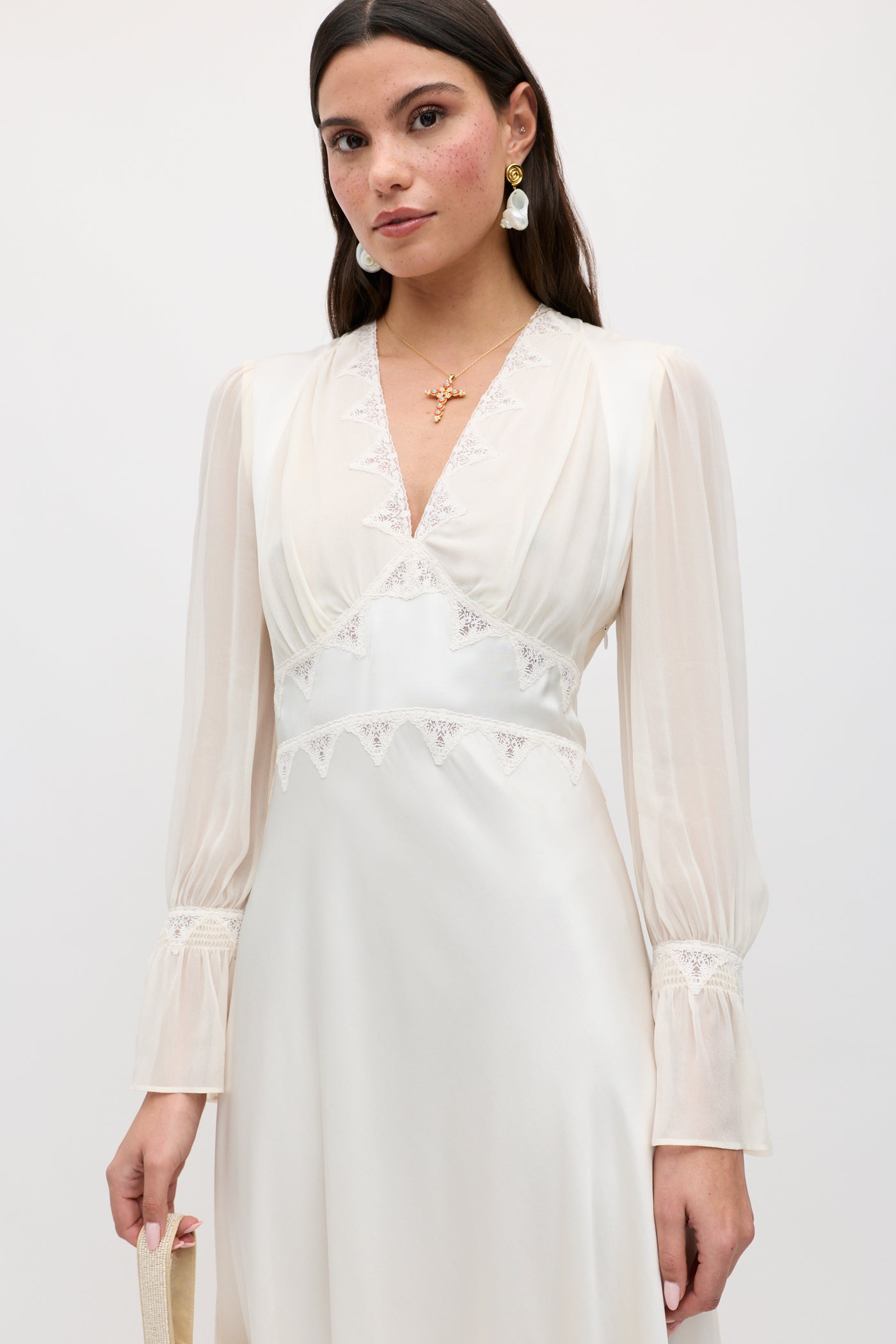 A woman in the Arlena - Pearl vintage midi dress, featuring delicate lace embroidery.