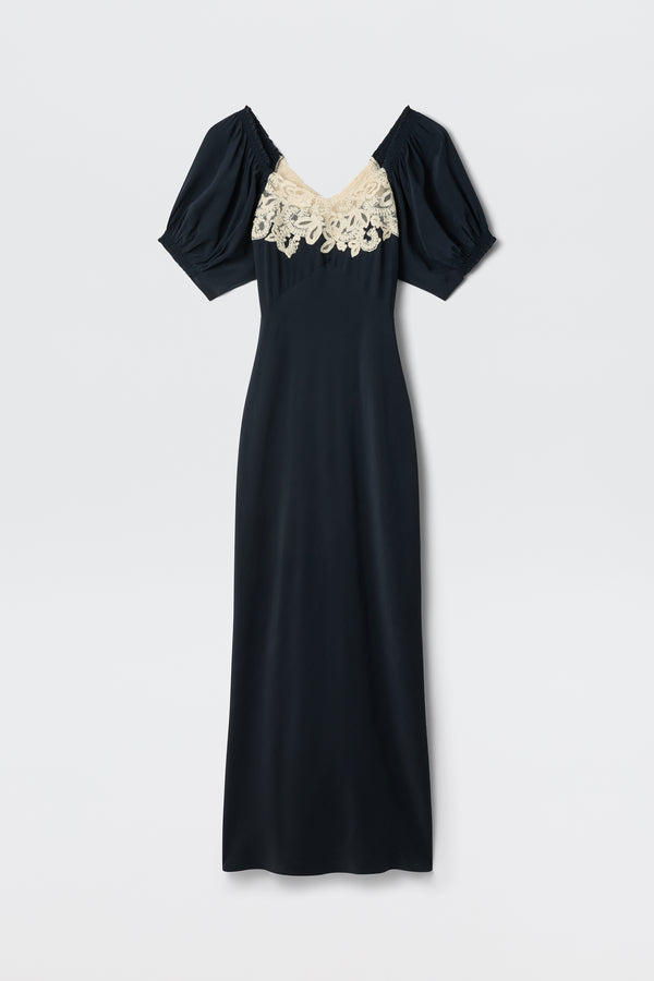 The Ilaria - Deep Navy is a long, short-sleeve dress with a V-neckline, cream lace detail across the chest, and puffed sleeves, featuring a simple and elegant silhouette.
