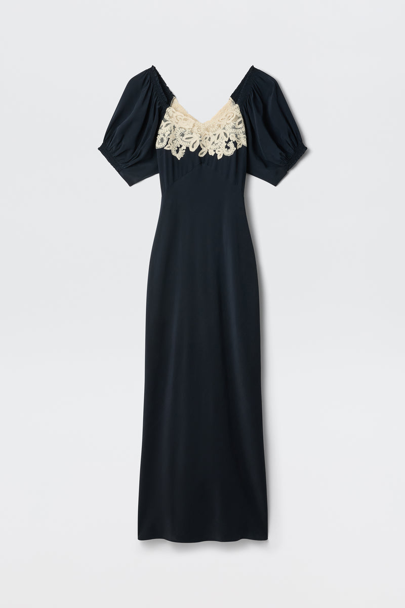 The Ilaria - Deep Navy is a long, short-sleeve dress with a V-neckline, cream lace detail across the chest, and puffed sleeves, featuring a simple and elegant silhouette.