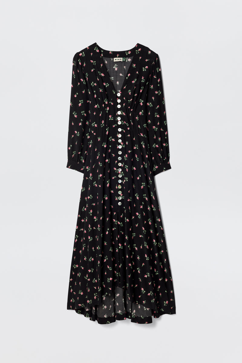 The Avalyn - Sienna Bud Black is a long-sleeved, black silk tea dress with a V-neckline, white buttons, vintage-style cuffs, and a pink and green floral print. Its loose, flowy silhouette offers an elegant, timeless look.