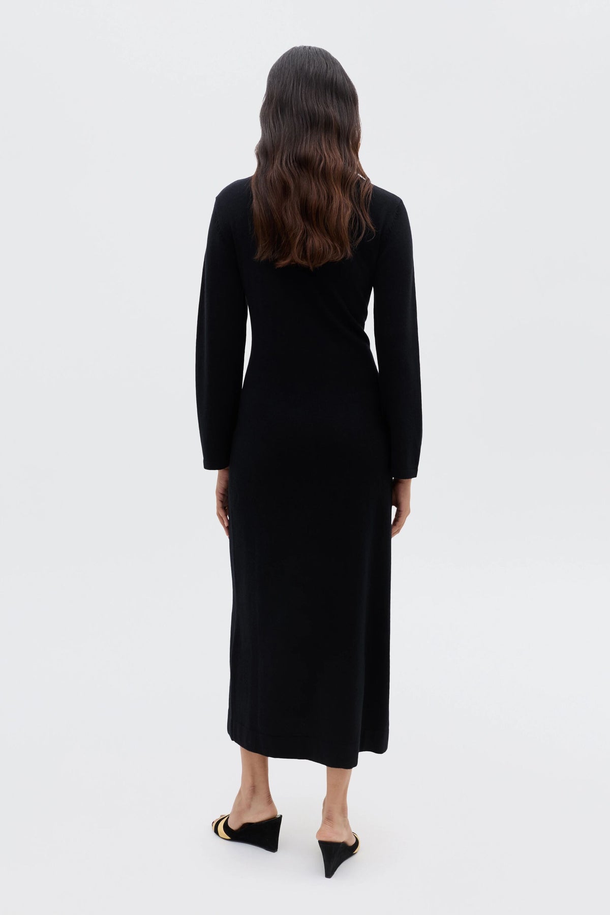 A woman in the Elliette - Black turtleneck dress embraces a minimalist style.