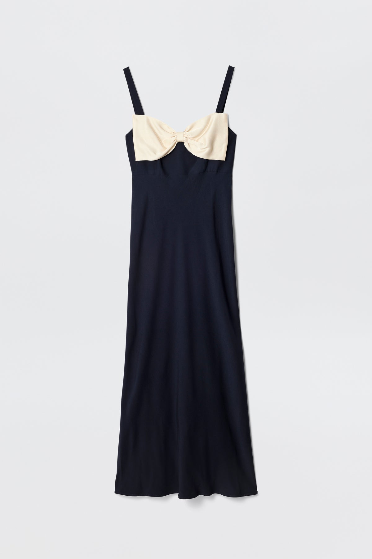 The Melisse is a sleeveless, ankle-length deep navy evening dress with spaghetti straps and a large cream-colored bow at the chest, shown against a plain white background.