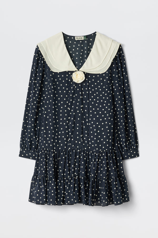 Valetta - Layla Dot Navy is a navy blue, long-sleeved dress with white polka dots, a cream sailor collar, bow detail at the neckline, and a ruffled hem.