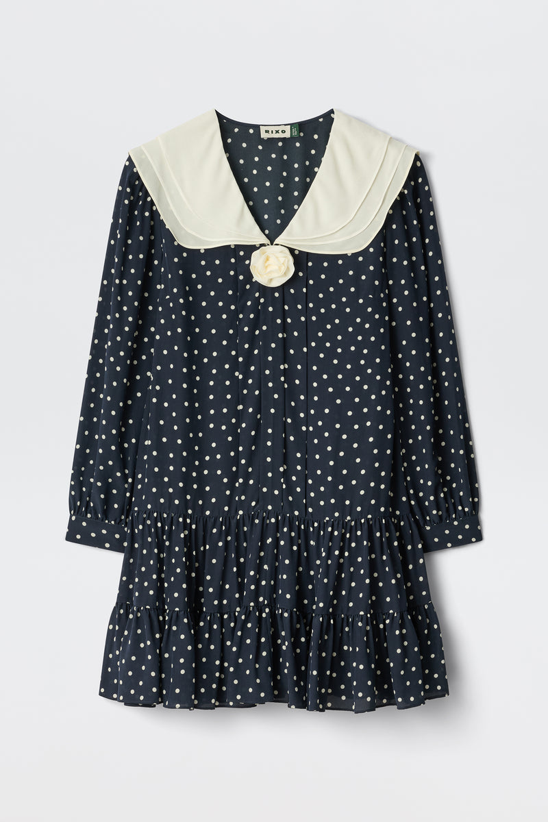 Valetta - Layla Dot Navy is a navy blue, long-sleeved dress with white polka dots, a cream sailor collar, bow detail at the neckline, and a ruffled hem.