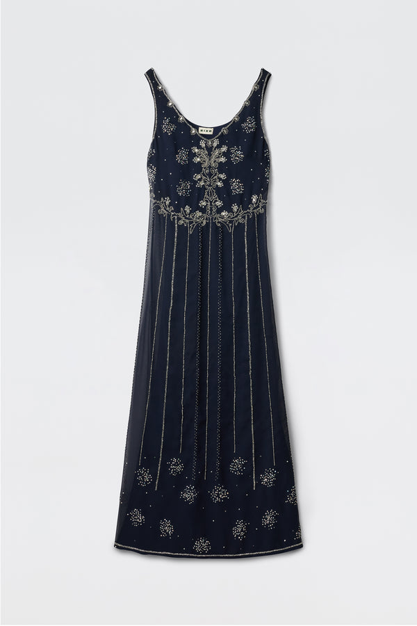 The Silvanna - Tilda Embellishment Navy is a sleeveless, floor-length dress in navy with silver floral embroidery and vertical lines, offering an elegant, classic look. The dress is displayed lying flat on a light background.