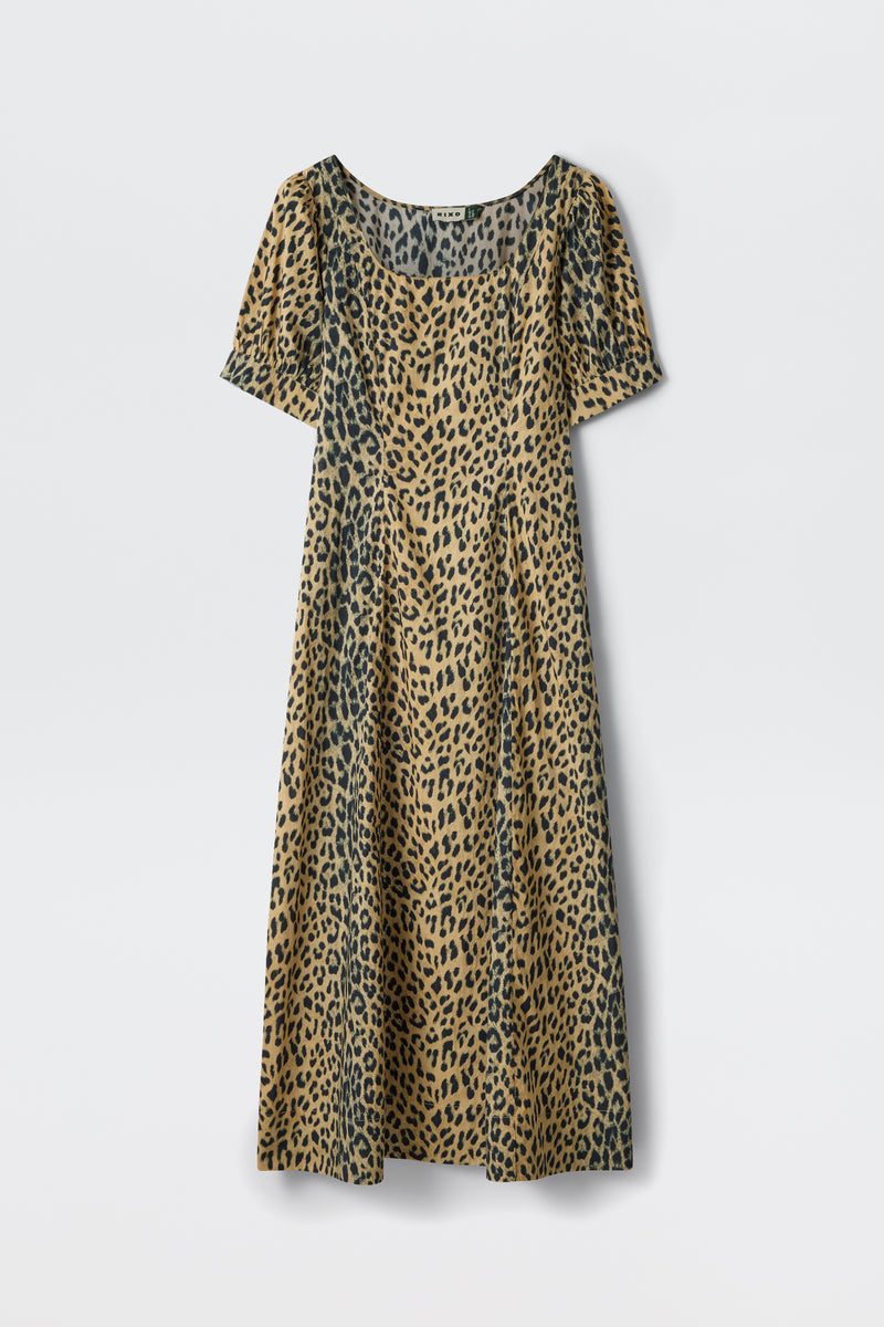 The Kathleen - Nina Leopard Brown is a short-sleeved, calf-length dress with a scoop neckline, featuring a tan and black leopard print, shown against a plain white background.