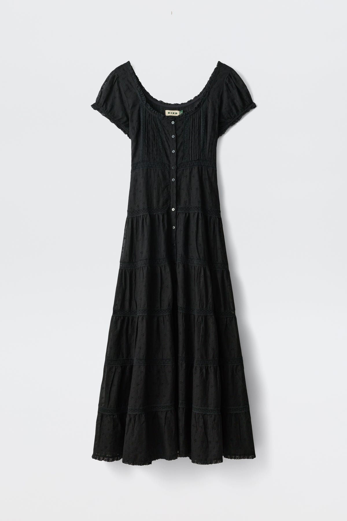 The Jaclyn - Black is an ankle-length, short-sleeve dress with a scoop neckline, button-down front, fitted bodice, flared tiered skirt, and subtle texture details. Shown against a plain white background.