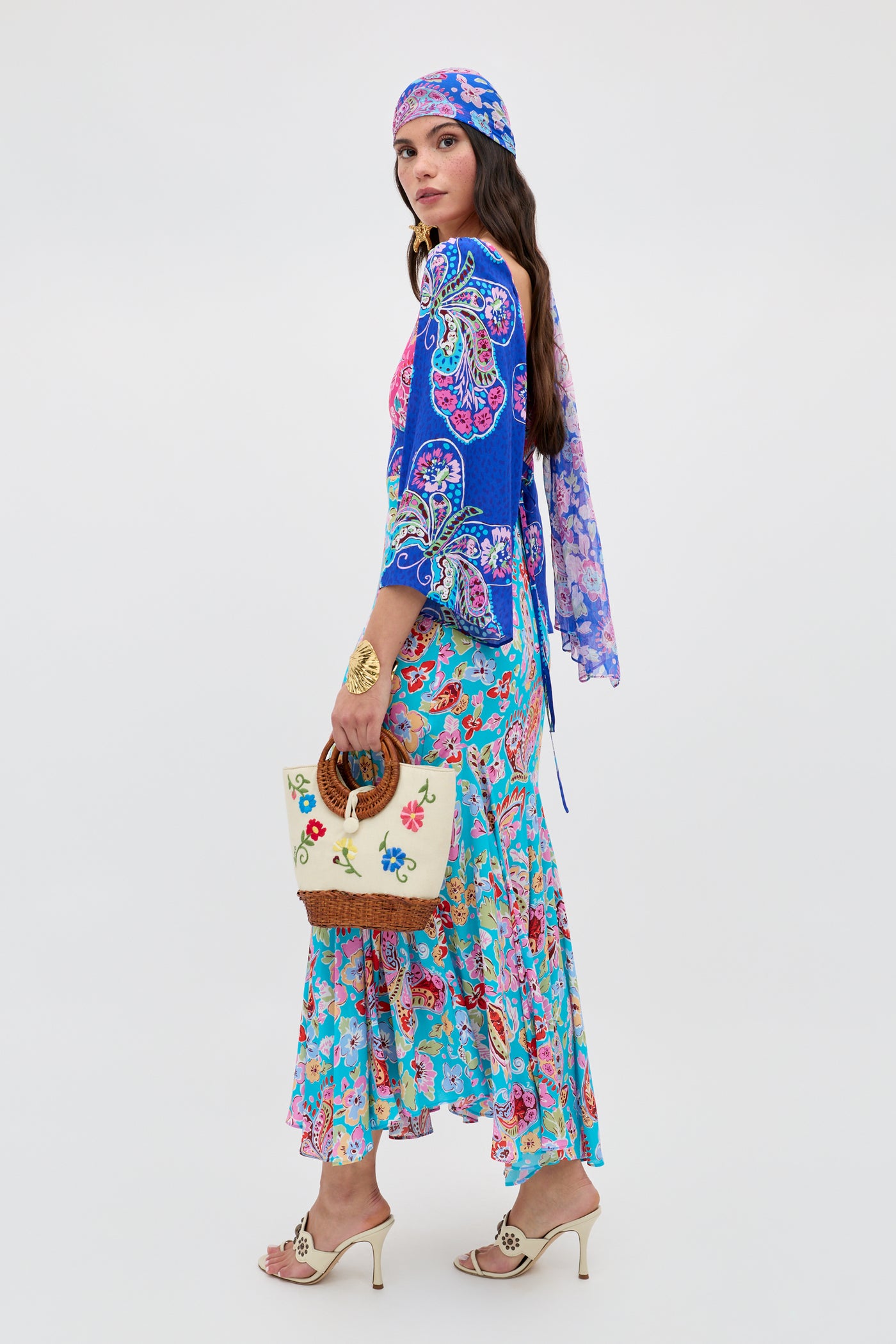 A woman in a bohemian look wears the Zelene Ombre Floral Embroidery Cream dress with a matching headscarf, cream hand-crafted bag with wicker handle, gold bracelet, and open-toe heels against a plain white background.
