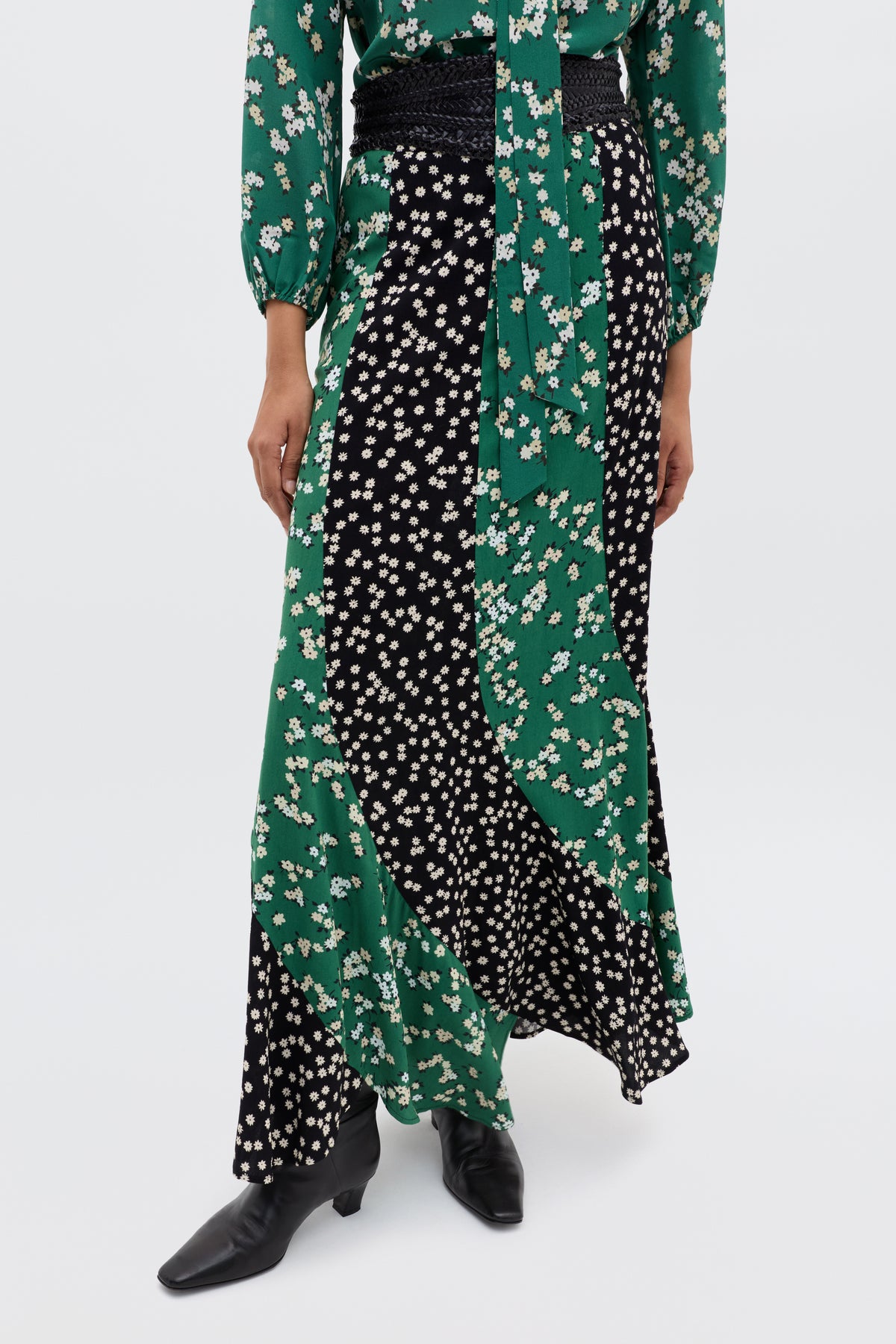 Wearing the Gracella - City Floral Mix Olive winter floral midi skirt with green and black sections featuring white flowers, paired with a matching green floral top and black heeled boots for easy transitional style.