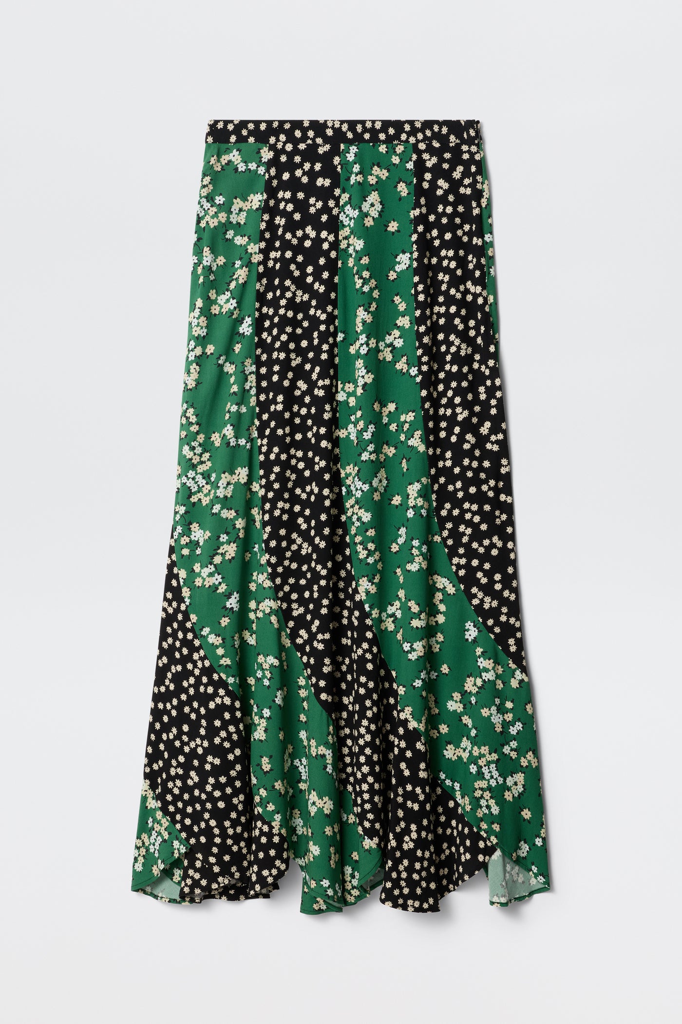 The Gracella - City Floral Mix Olive is a long, flowy midi skirt with alternating black and green panels in a small white floral print. It features a mid-rise waist, slightly flared hem, and is perfect for transitional dressing.