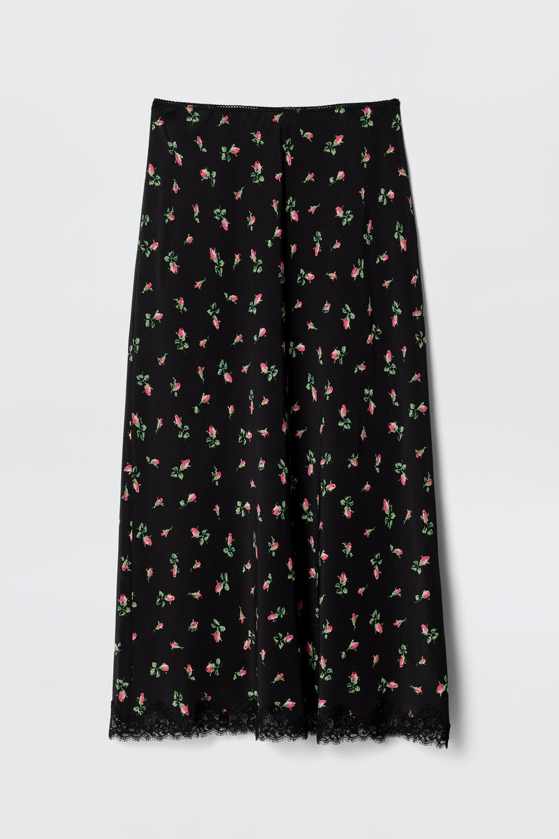 The Stassie - Sienna Bud Black is a vintage-inspired black midi skirt featuring a pink and green floral pattern and lace-trimmed hem. Its lightweight fabric and relaxed, flared fit make it perfect for co-ord styling.