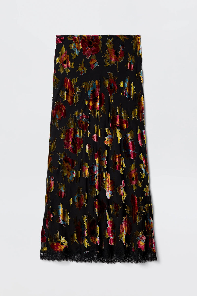 The Stassie - Countryside Devoré Black is a black midi skirt with red, gold, and purple floral patterns and a lace-trimmed hem, shown flat on a plain white background.