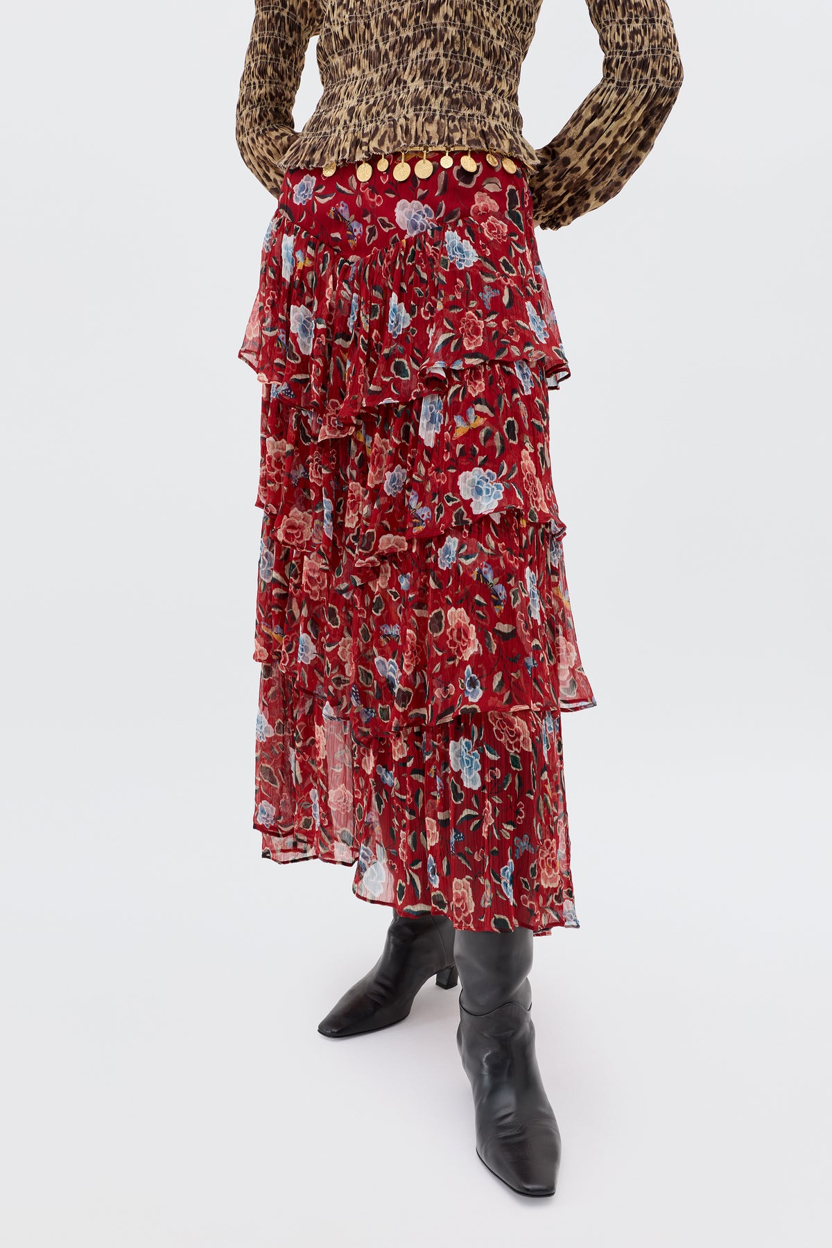 A person wearing a leopard print long-sleeve top, the Taryn - Butterfly Floral Burgundy skirt in crinkled georgette, and black knee-high boots stands against a plain background.