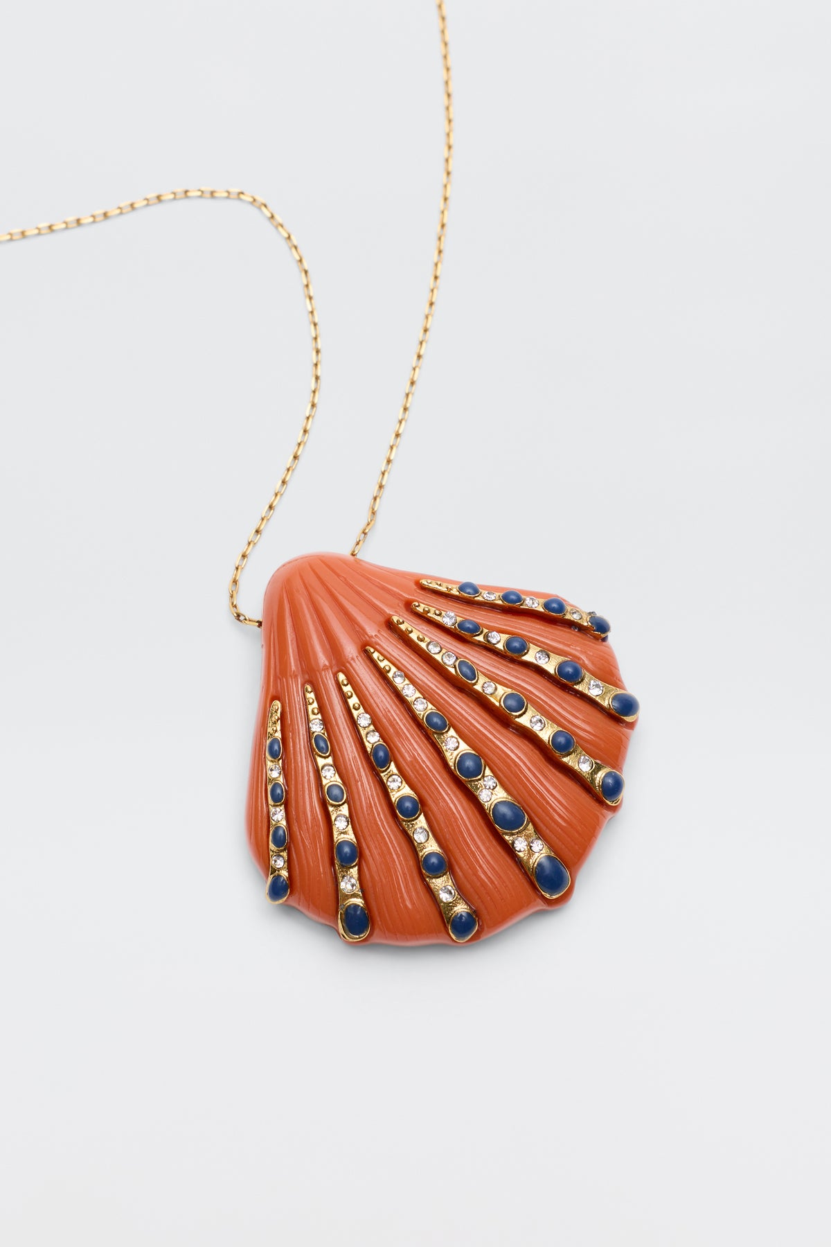 Leanira - Orange is a vintage-inspired necklace with a gold-plated chain and an orange seashell-shaped pendant, finished with gold and blue bead accents radiating from the shell's hinge.