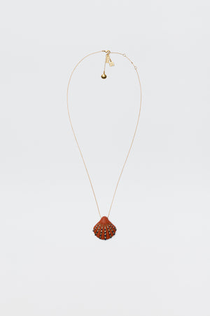 The Leanira - Orange necklace features a scallop shell-shaped pendant with small decorative studs on a gold-plated chain, shown against a plain white background.